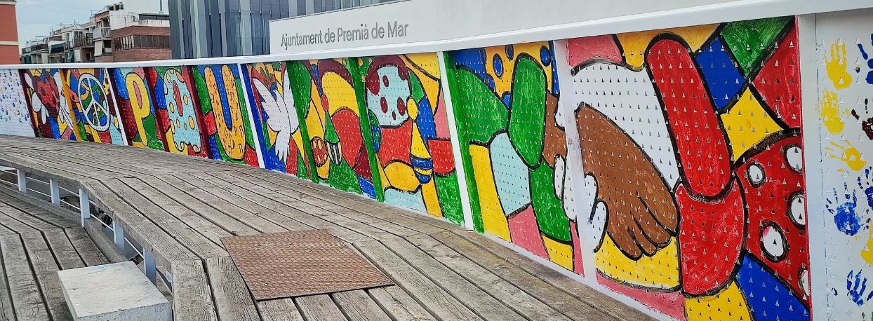 Mural pintat a la grada de la plaa dels Pasos Catalans per alumnes de P5 d'escoles de Premi de Mar, amb motiu del Dia Escolar per a la No-Violncia i la Pau 2025 (DENIP), dirigits pel pintor Pol Peir.